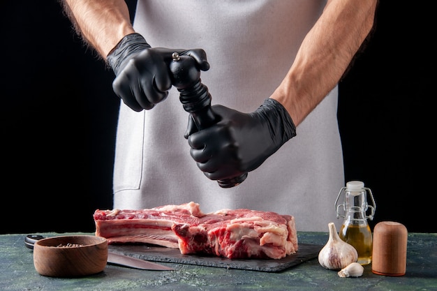 Front view male butcher spicing up meat slice on dark surface