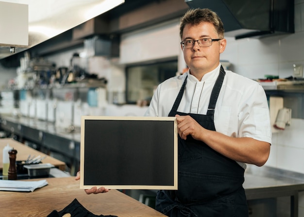 Front view of male chef holding blackboard