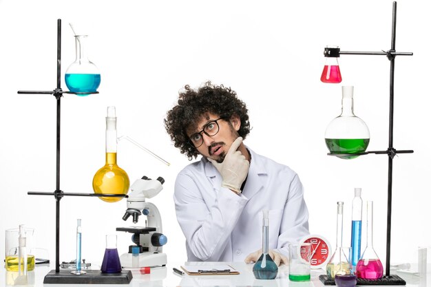 흰색 공간에 생각 솔루션으로 테이블 앞에 앉아 의료 소송에서 전면보기 남성 화학자