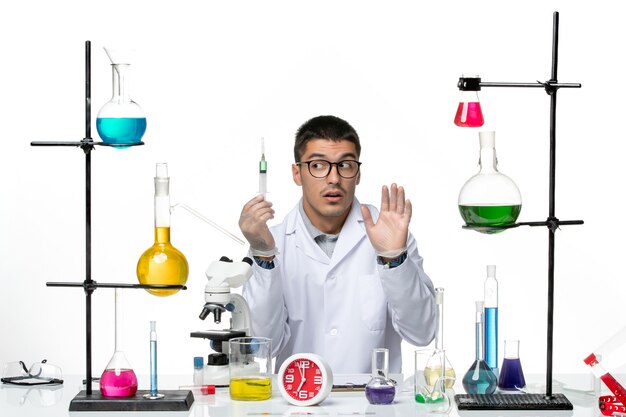 Вид спереди мужской химик в белом медицинском костюме, держащий инъекцию на белом фоне, вирусная наука, пандемическая лаборатория covid