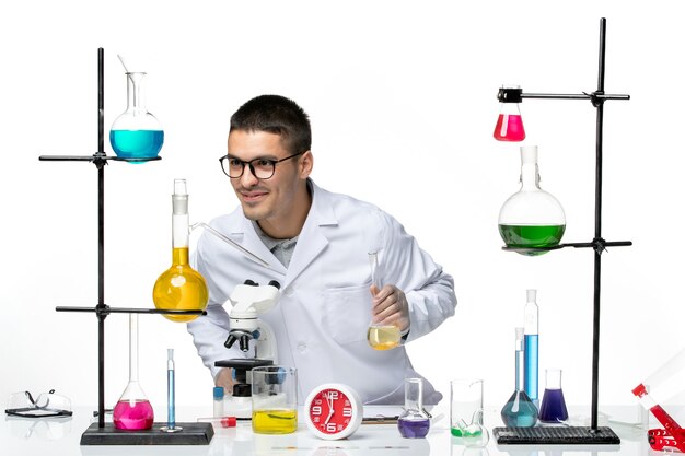 白い背景のラボウイルス科学covidパンデミックのソリューションで作業している白い医療スーツの正面図男性化学者