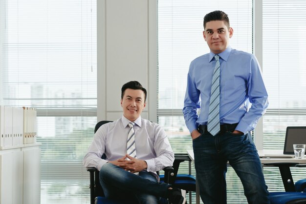 Front view of male colleagues looking at camera in their office