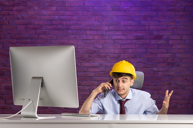 Free photo front view male constructor behind office desk talking at phone