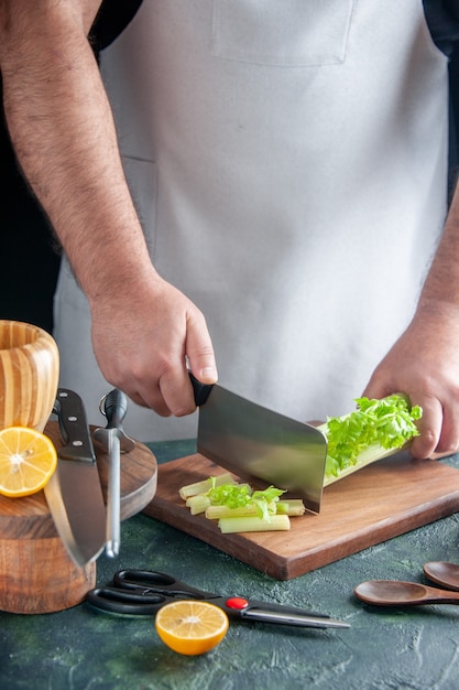 Вид спереди мужчина повар резка сельдерея на темном столе салат диета еда цвет фото еда здоровье
