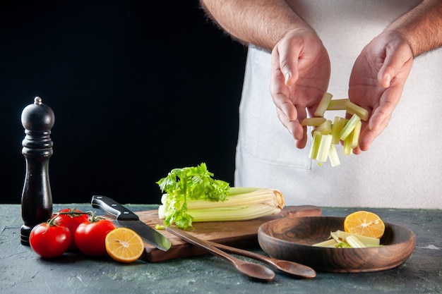 Front view male cook cutting celery on dark wall salad diet meal photo food colors cooking kitchen