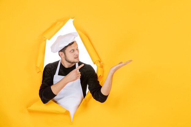 Front view male cook in white cape and cap on yellow ripped job color photo kitchen man cuisine