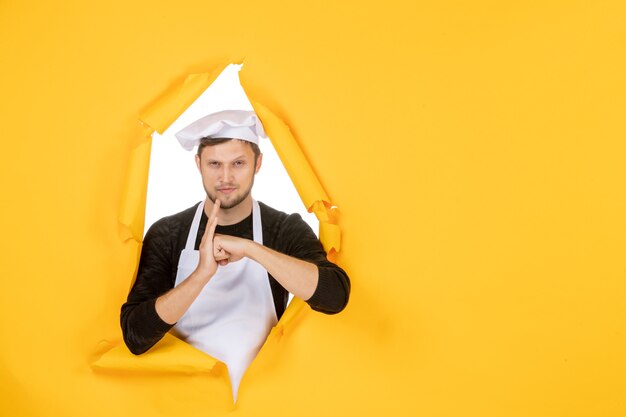 Front view male cook in white cape and cap on yellow ripped job color white photo kitchen food man cuisine