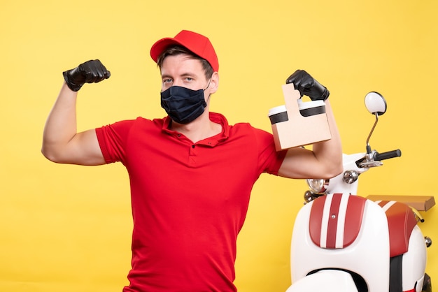 Front view male courier in black mask with coffee cups on yellow job virus covid- delivery uniform work service