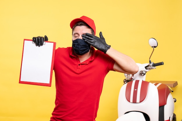 Front view male courier in black mask with file note on yellow job covid delivery pandemic work service virus