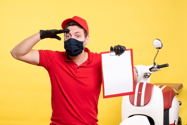 Foto gratuita corriere maschio vista frontale in maschera nera con nota di file su lavoro uniforme gialla consegna covid virus servizio di lavoro pandemico