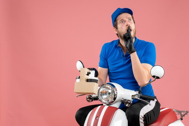 Front view male courier in blue uniform holding coffee on pink color job fast-food delivery service worker work bike