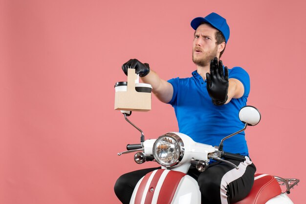 Front view male courier in blue uniform holding coffee on pink color job fast-food service worker delivery work bike