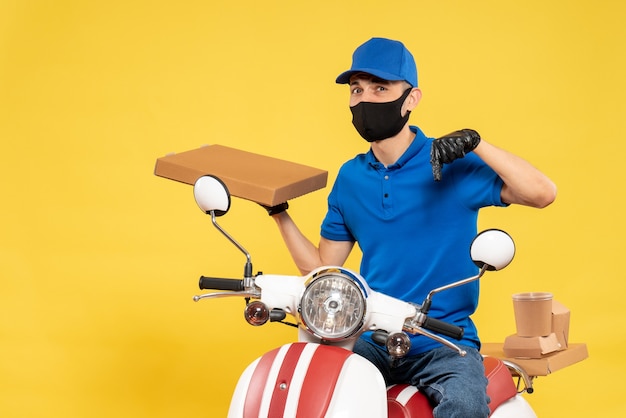 Foto gratuita corriere maschio di vista frontale in scatola di cibo della tenuta dell'uniforme blu sulla bici di lavoro di servizio di lavoro di consegna di covid di pandemia di virus giallo