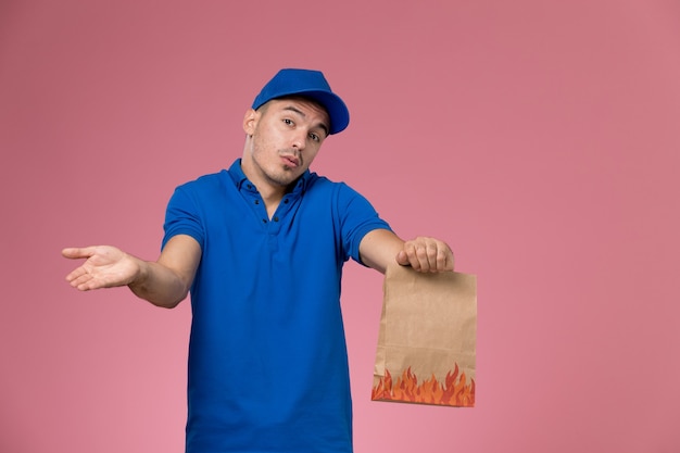 분홍색 벽에 종이 음식 패키지를 들고 파란색 제복을 입은 전면보기 남성 택배, 직장인 유니폼 서비스 제공