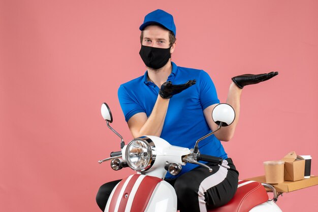 Front view male courier in blue uniform and mask on pink service virus bike fast-food covid- work job