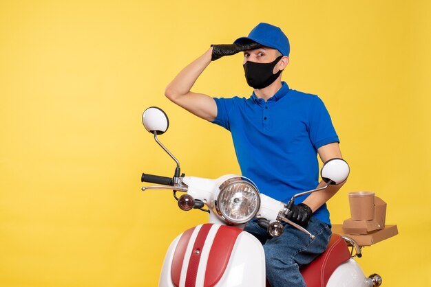 青い制服を着た正面図の男性宅配便と黄色い自転車のパンデミック作業のマスク