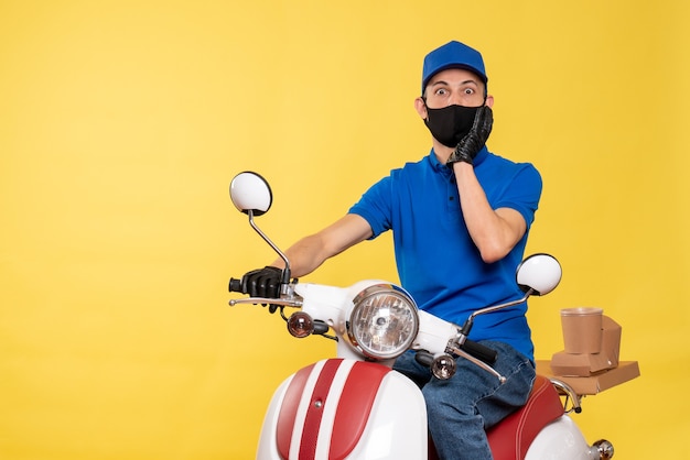 Курьер-мужчина, вид спереди в синей форме и маске на желтом велосипеде, пандемия работы, доставка вируса covid- job