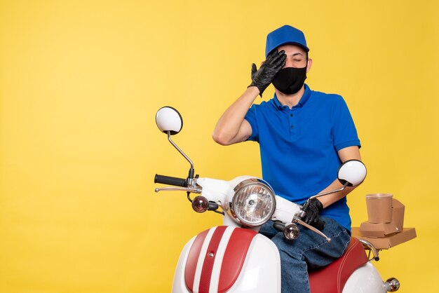 青い制服を着た正面図の男性宅配便と黄色いウイルスのマスクジョブcovid配信サービス作業パンデミックバイク
