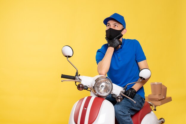 Курьер-мужчина, вид спереди в синей форме и маске на желтом, работа covid - пандемическая служба, доставка велосипедов, вирус