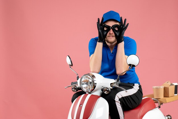 Front view male courier in blue uniform on a pink food fast-food bike delivery job color work service