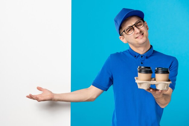 Front view of male courier in blue uniform with coffee on blue 