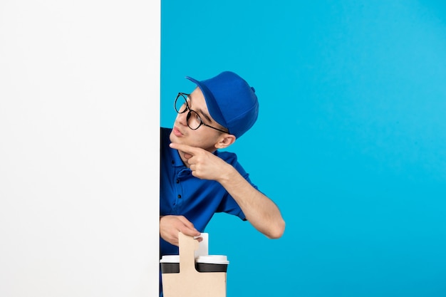 Front view of male courier in blue uniform with coffee on blue 