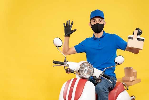 黄色のパンデミックバイクcovid-jobdeliveryウイルスサービスでコーヒーと青い制服を着た正面図の男性宅配便