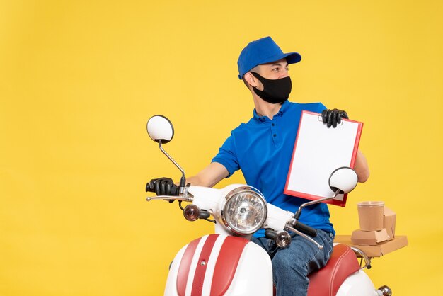 Front view male courier in blue uniform with file note on the yellow bike work covid- job virus delivery service