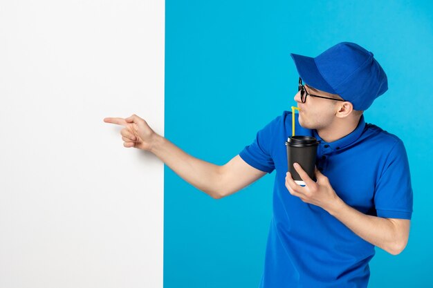 Front view male courier drinking coffee on a blue 