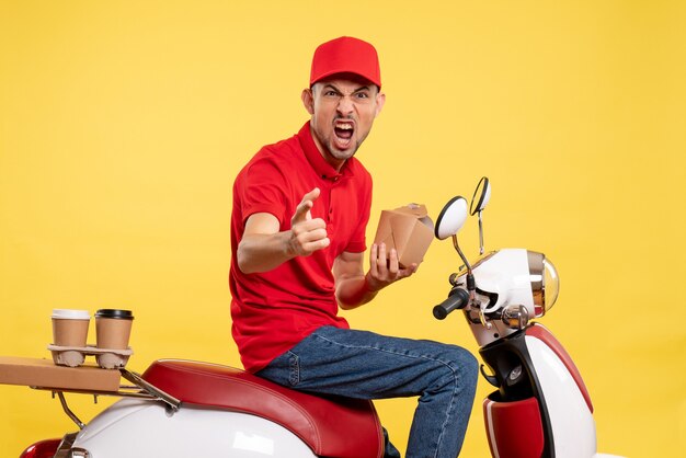 Front view male courier holding little delivery food screaming on yellow bike delivery color work worker uniform service food