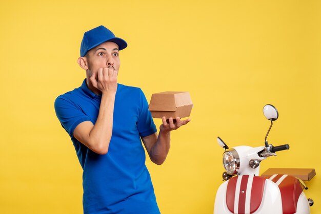 黄色の仕事の色で小さな食品パッケージを保持している正面図の男性の宅配便サービス作業配達制服自転車