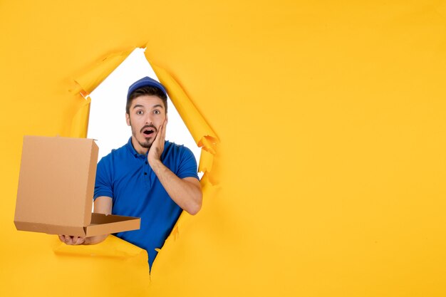 Front view male courier holding opened pizza box on a yellow space