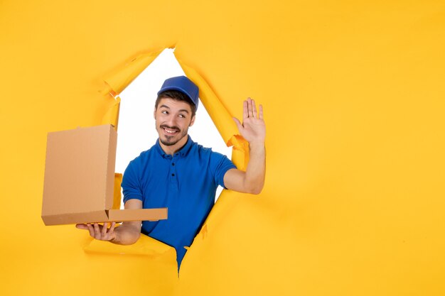 Front view male courier holding opened pizza box on yellow space