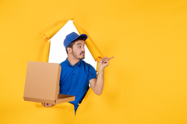 Front view male courier holding opened pizza box on yellow space