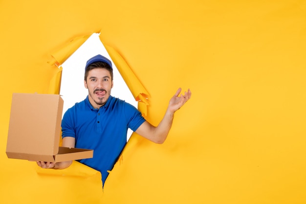 Free photo front view male courier holding opened pizza box on yellow space