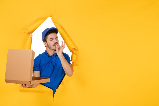 Front view male courier holding opened pizza box on yellow space