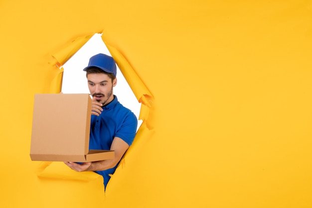 Front view male courier holding pizza box on yellow space