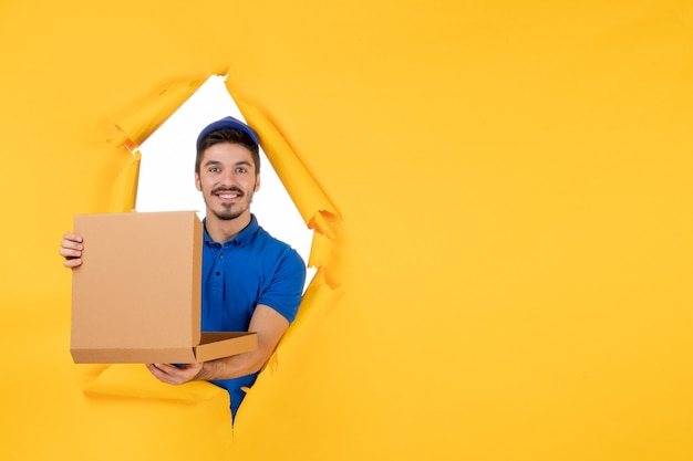 Free photo front view male courier holding pizza box on yellow space