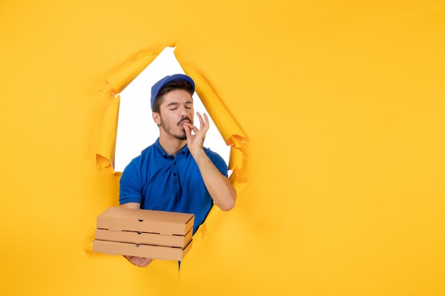 Free photo front view male courier holding pizza boxes on yellow space