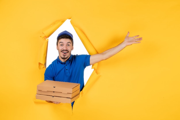 Вид спереди мужской курьер, держащий коробки для пиццы на желтом пространстве