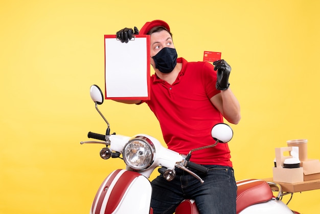 Free photo front view male courier in mask holding file note and bank card on a yellow