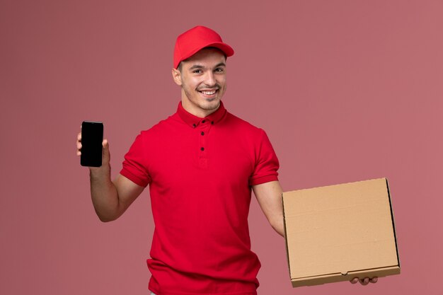 빨간색 유니폼과 케이프 핑크 벽 서비스 작업 남성 배달 유니폼에 전화와 함께 음식 상자를 들고 전면보기 남성 택배