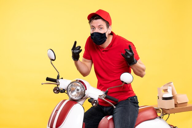 Free photo front view male courier in red uniform and mask on yellow