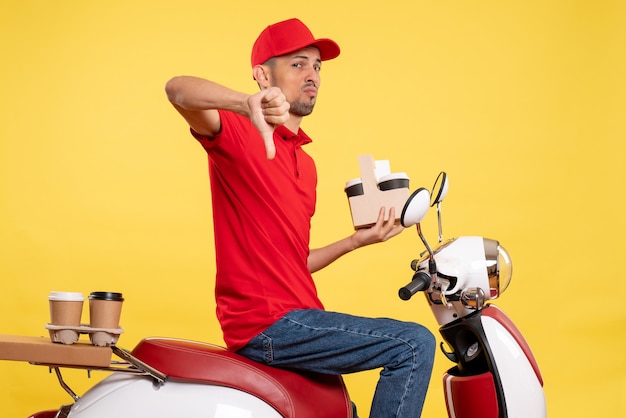 Front view male courier in red uniform with coffee on yellow service color uniform work job delivery worker bike