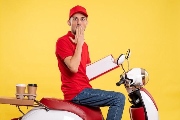 Corriere maschio di vista frontale in uniforme rossa con la nota del file sul servizio di lavoratore uniforme del lavoro di consegna di colore della bici gialla