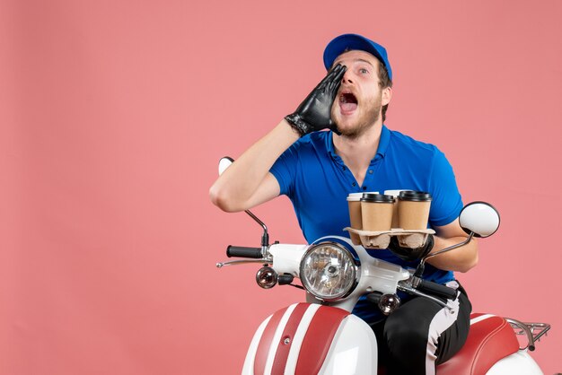 Front view male courier sitting on bike and holding coffee cups on pink 