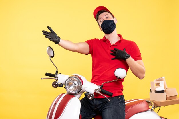 Front view male courier in uniform gloves and mask on yellow 