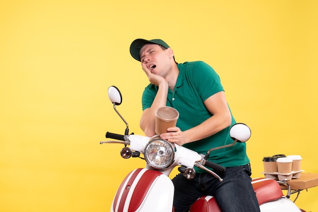 Front view male courier in uniform holding coffee cup suffering from toothache on a yellow 