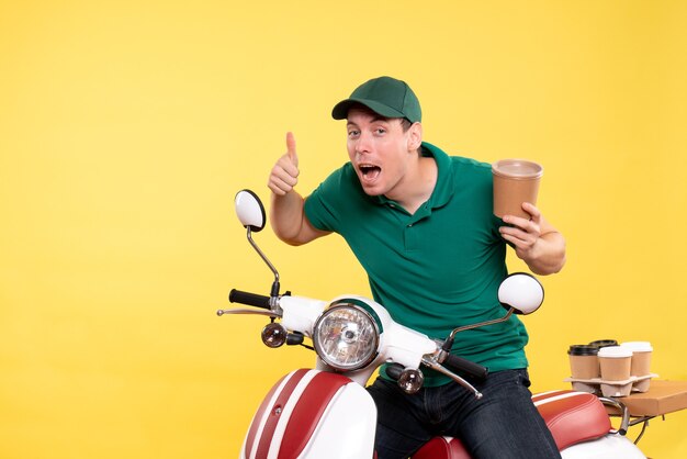 Front view male courier in uniform holding coffee cup on a yellow 