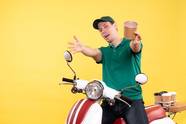 Front view male courier in uniform holding coffee cup on yellow 